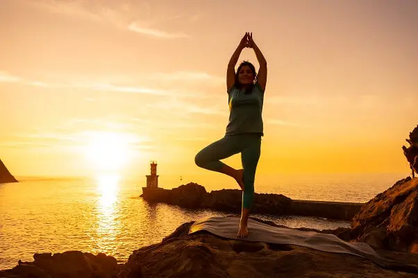 Woman doing meditation yoga exercises on beach