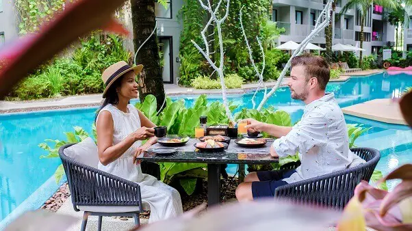 Couple having breakfast by pool during vacation