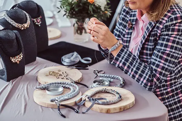 Elegantly dressed woman makes handmade necklaces